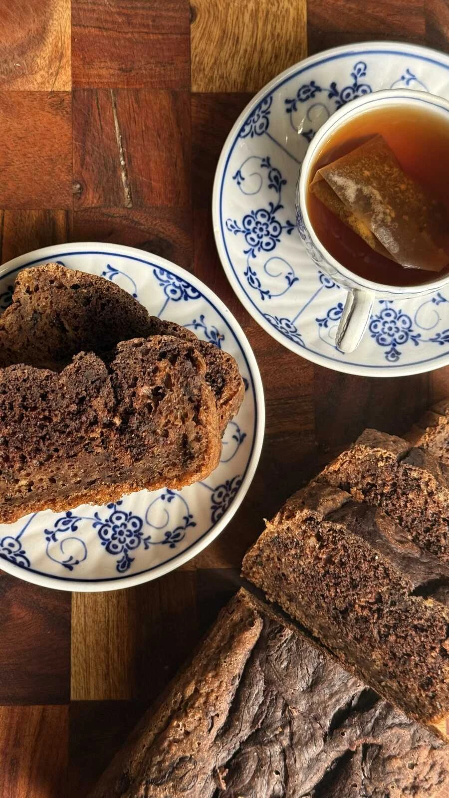 Saftigt bananbröd med smält choklad på tallrik intill en kopp med te