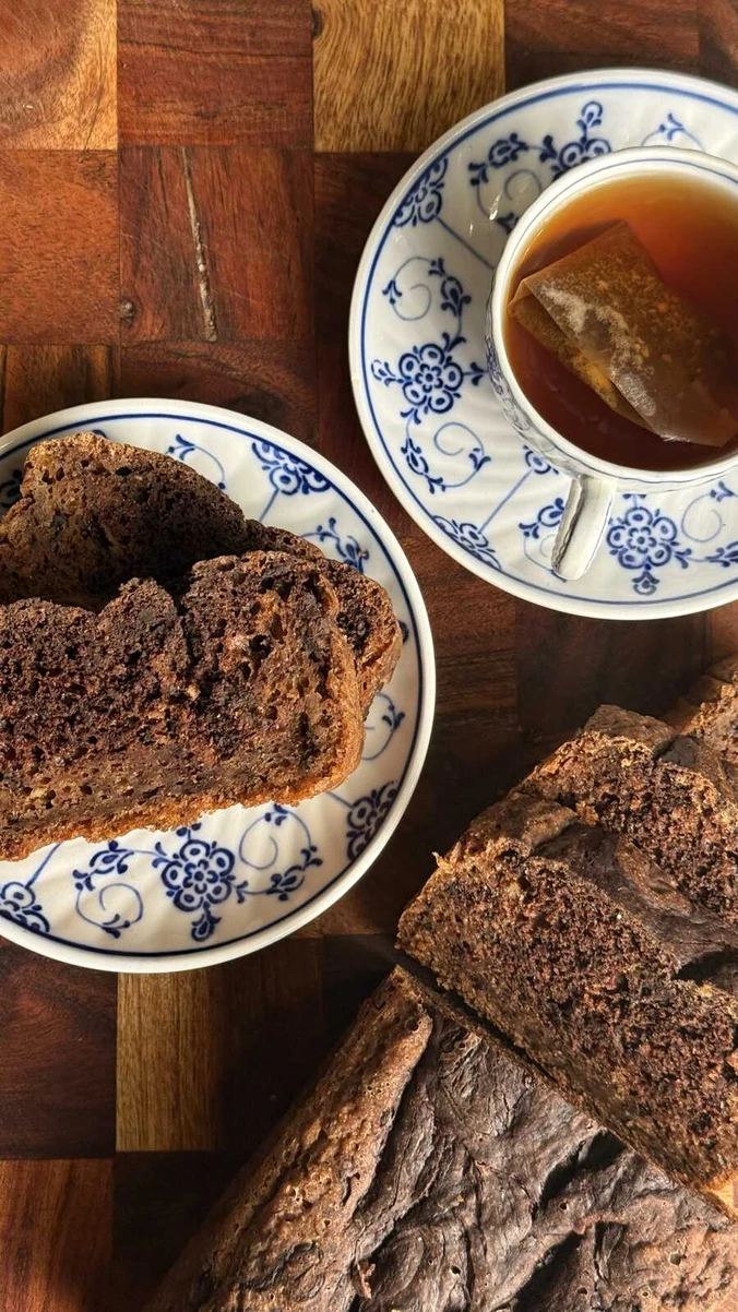 Saftigt bananbröd med smält choklad på tallrik intill en kopp med te